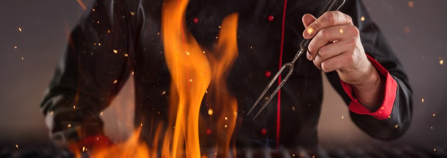 Closeup of chef holding fork above the grill. Concept of food preparation, ready for product placement.